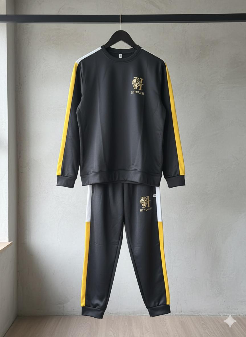 Black and yellow tracksuit with brand logo on a hanger against a gray wall.