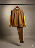 Brown tracksuit with yellow stripes on a hanger against a gray background