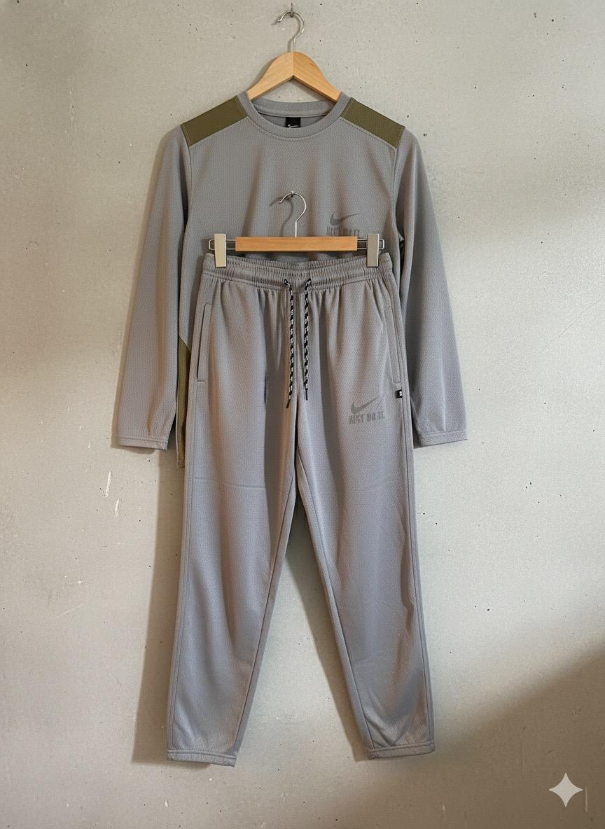 Gray tracksuit with Nike logo on a hanger against a plain wall.